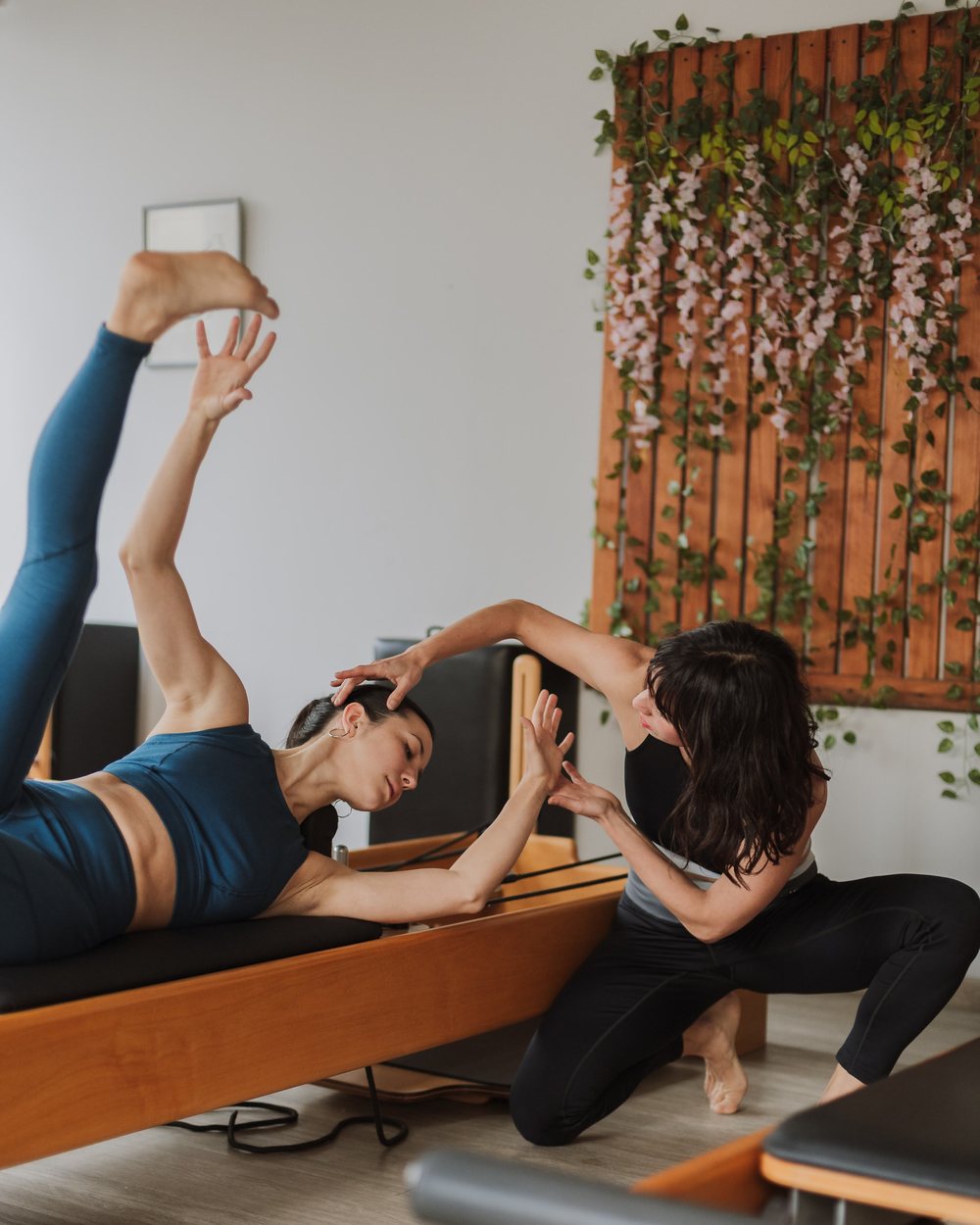 Clase privada de Pilates: la profe acompaña y corrige a la alumna sobre el Reformer